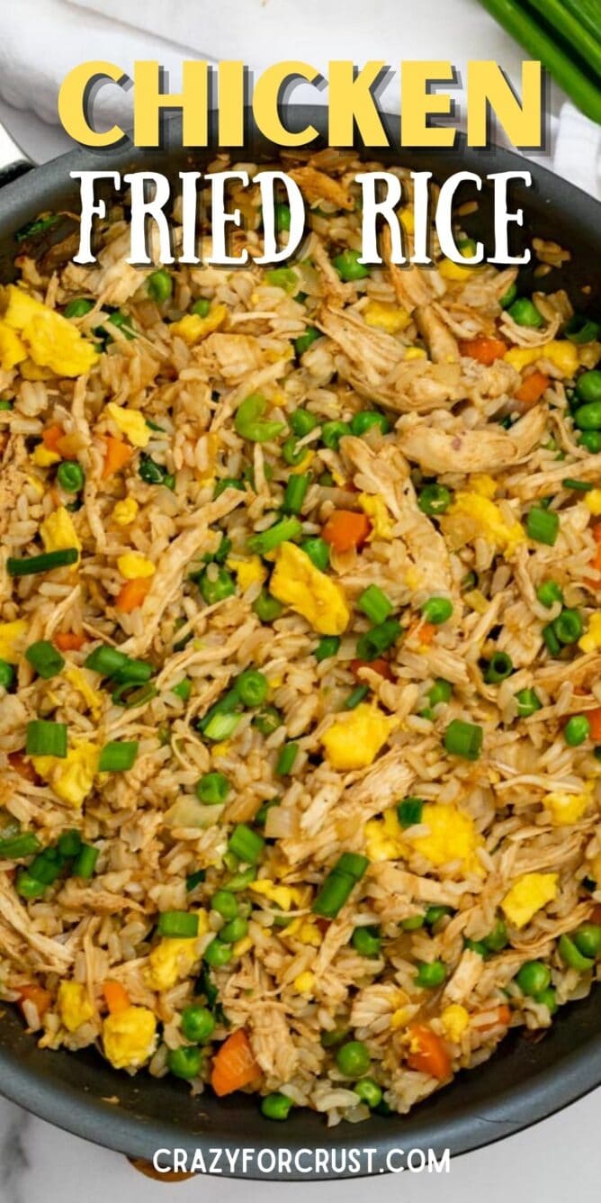 Overhead shot of chicken fried rice in frying pan with recipe title on top of image