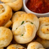 Close up shot of garlic knots next to marinara dipping sauce