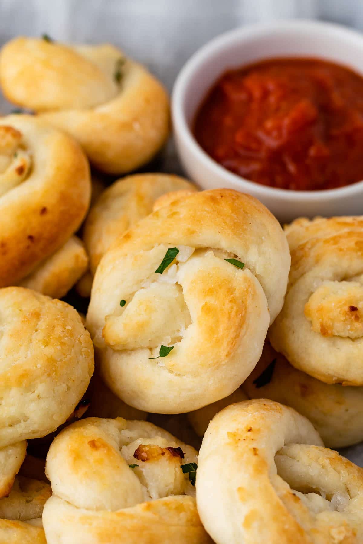 Close up shot of garlic knots next to marinara dipping sauce