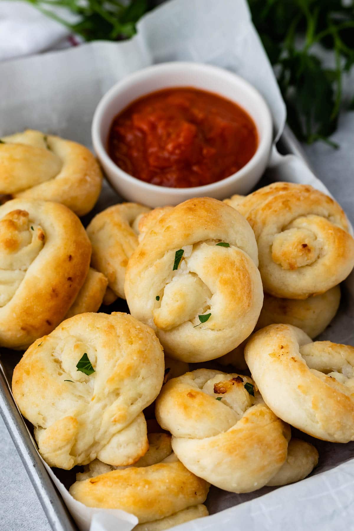 Close up shot of garlic knots next to marinara dipping sauce