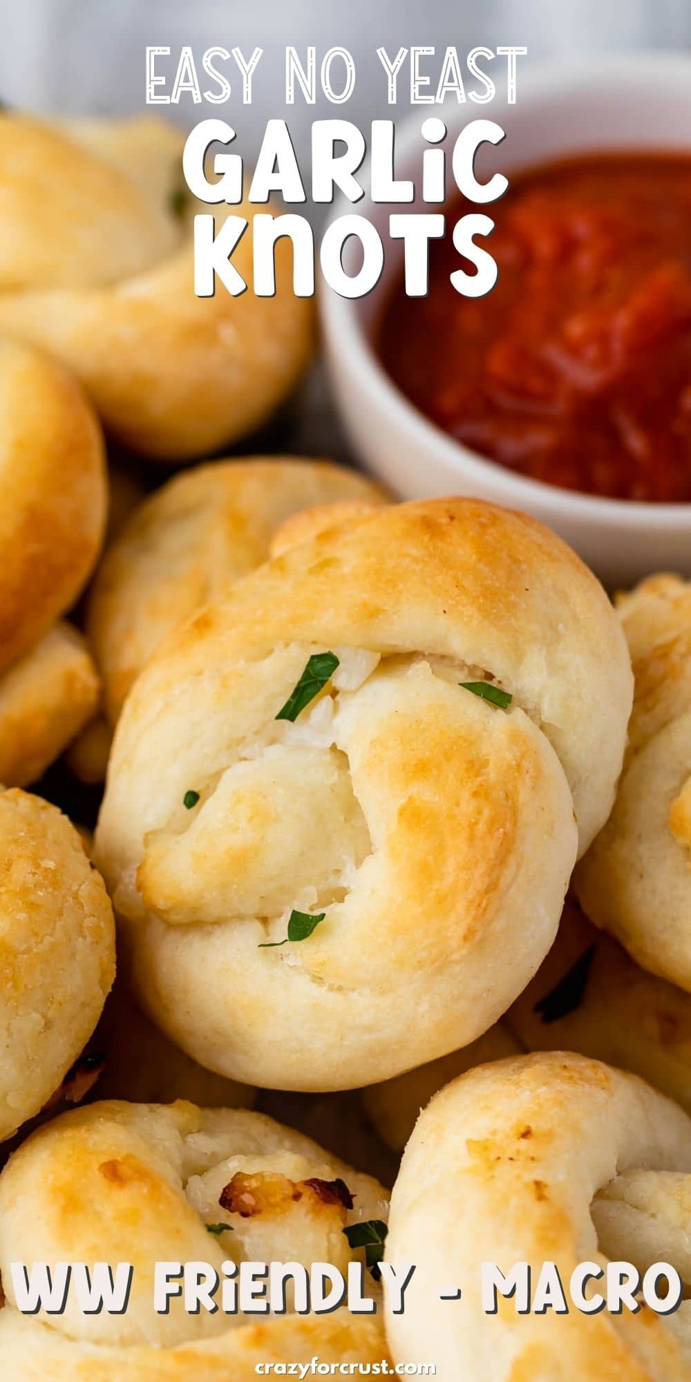 Close up shot of garlic knots next to dipping sauce and recipe title on top of image