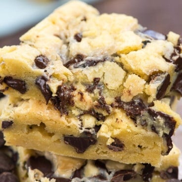 Stack of chocolate chip gooey cake bars with chocolate chips around the base