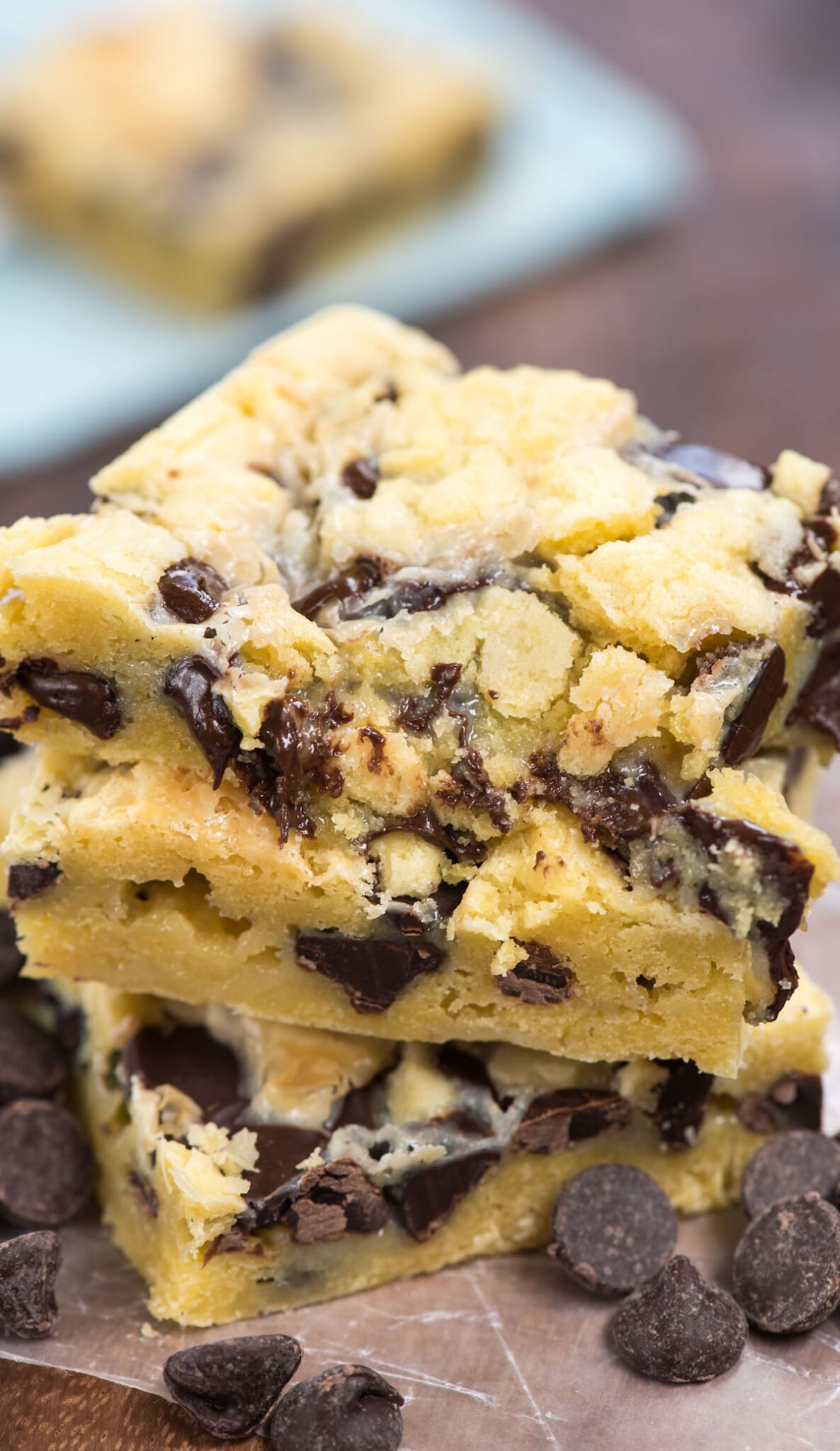 Stack of chocolate chip gooey cake bars with chocolate chips around the base