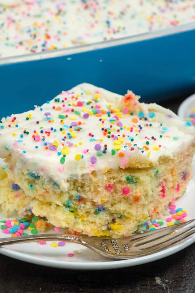 One piece of homemade funfetti cake on a plate with corner bite missing