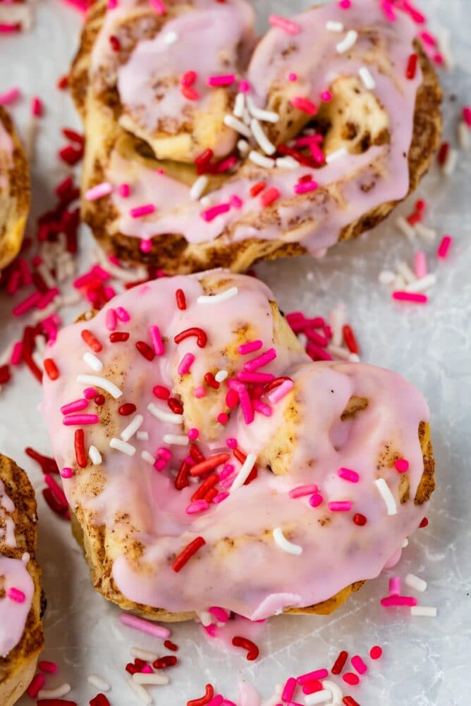 heart shaped cinnamon roll with pink icing and sprinkles