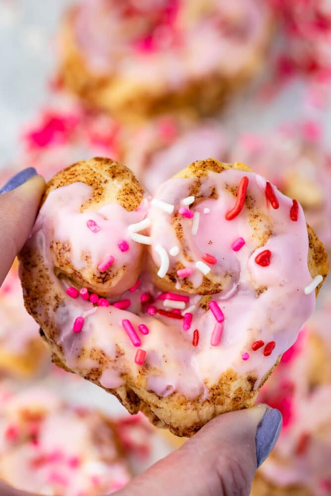 heart shaped cinnamon roll with pink icing and sprinkles