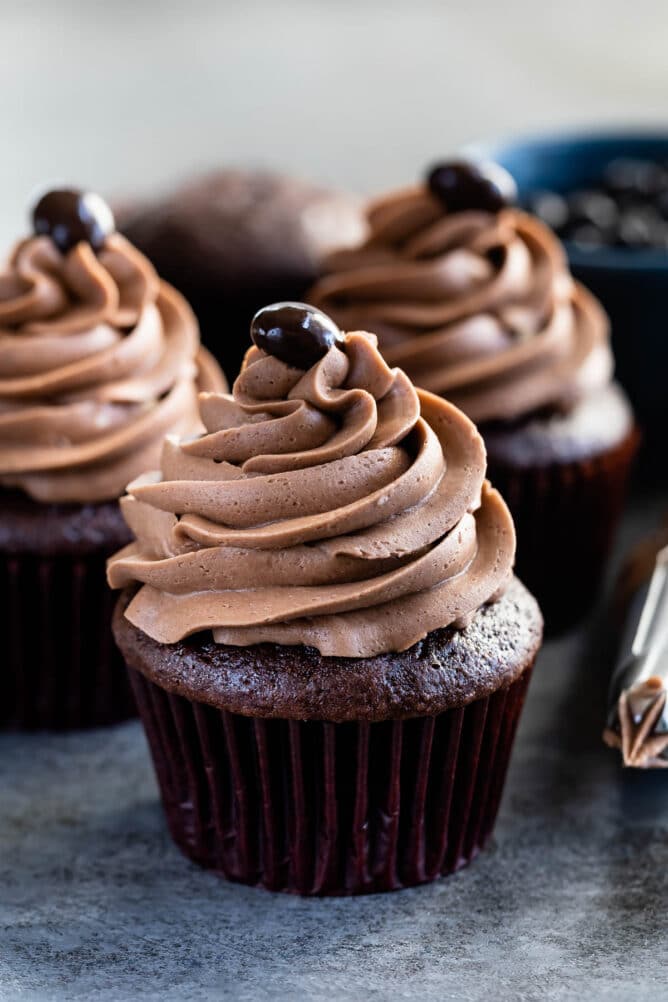 Three chocolate cupcakes topped with mocha frosting and a chocolate covered coffee bean