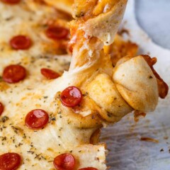 One piece of pizza being pulled apart from larger pizza