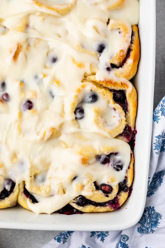 close up of corner of pan showing blueberry rolls with lemon glaze