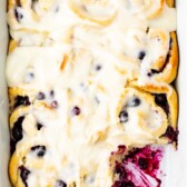 overhead shot of blueberry cinnamon rolls with one missing and lemon glaze