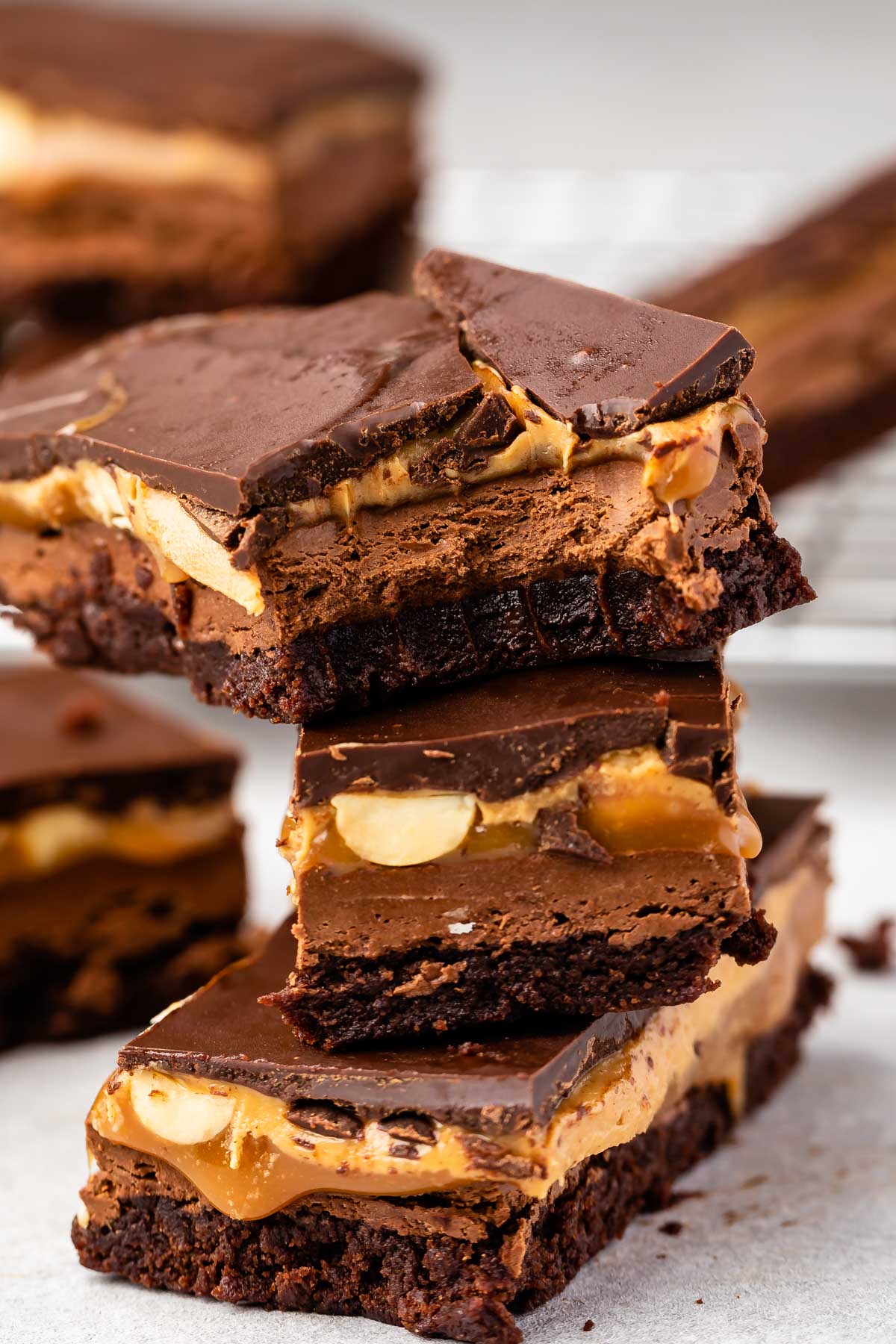 Close up shot of three snicker brownie bars stacked on top of eachother