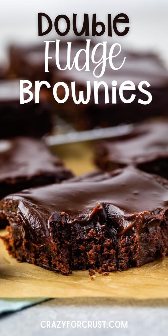 Close up shot of a double fudge brownie with corner bite missing and recipe title on top of image