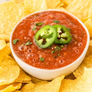 One bowl of easy salsa topped with sliced jalapenos surrounded by tortilla chips