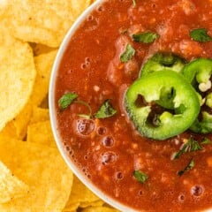 One bowl of easy salsa topped with sliced jalapenos surrounded by tortilla chips
