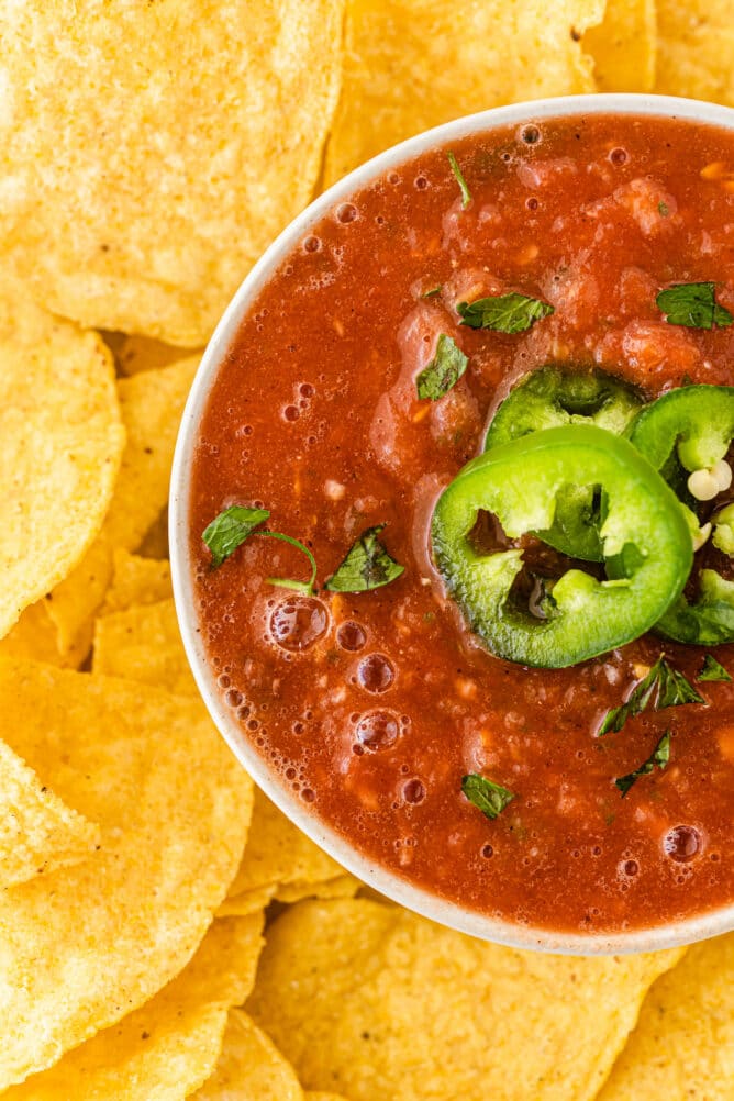 One bowl of easy salsa topped with sliced jalapenos surrounded by tortilla chips