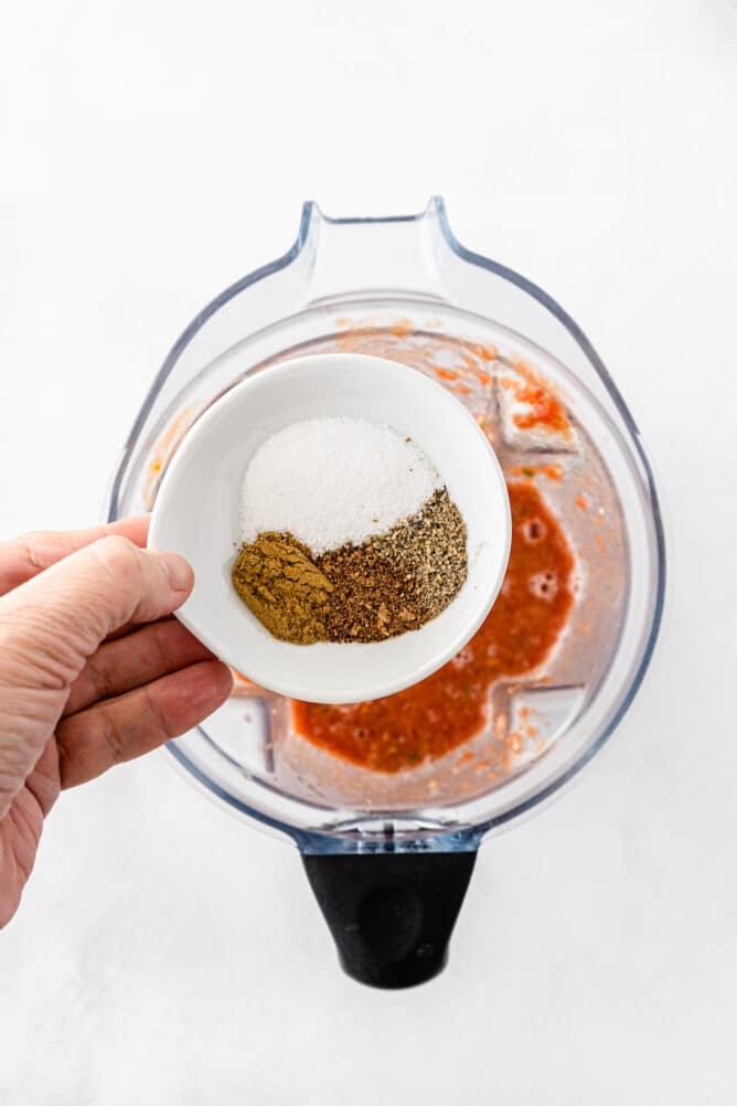 Overhead shot of seasonings in small bowl over blended salsa