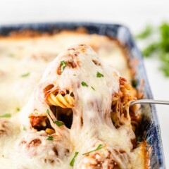 A spoonful of meatball casserole being pulled from casserole dish