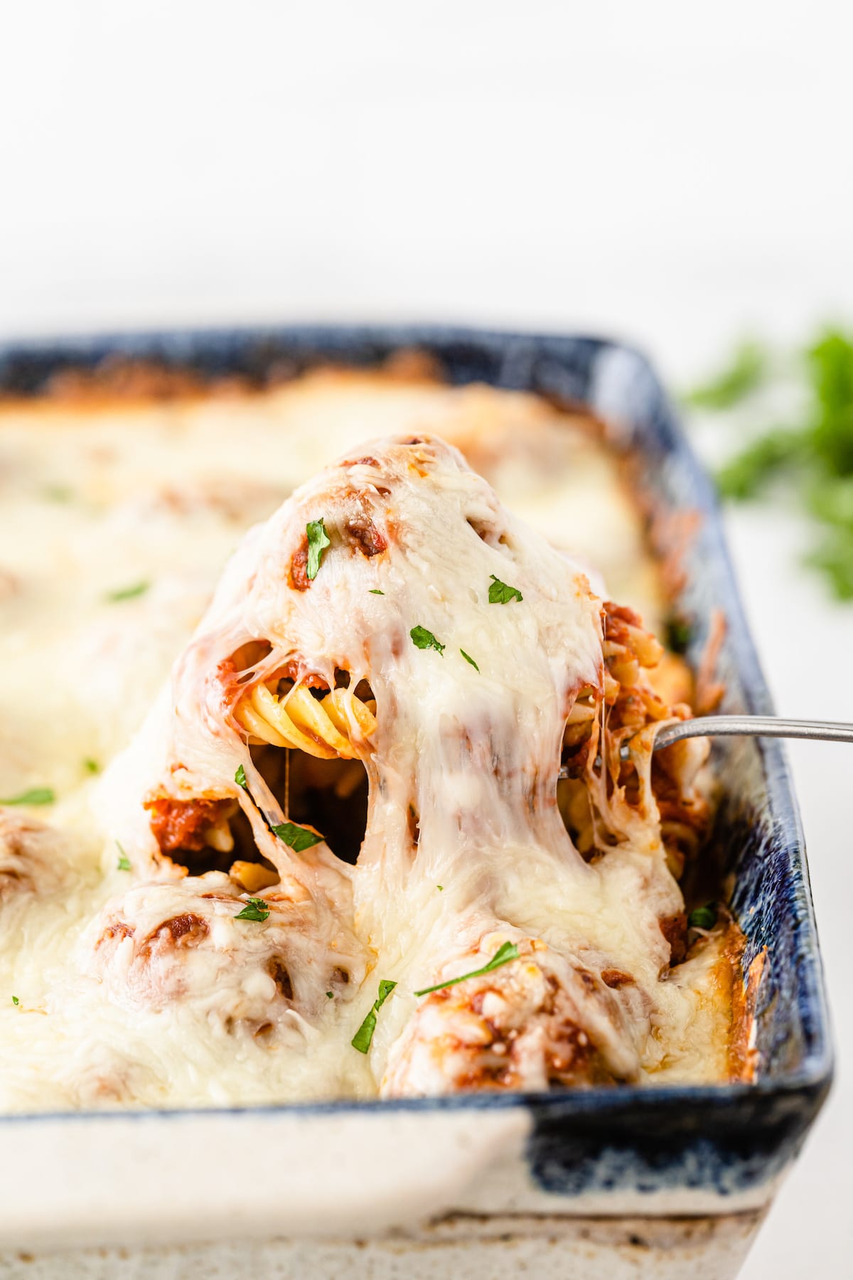 A spoonful of meatball casserole being pulled from casserole dish