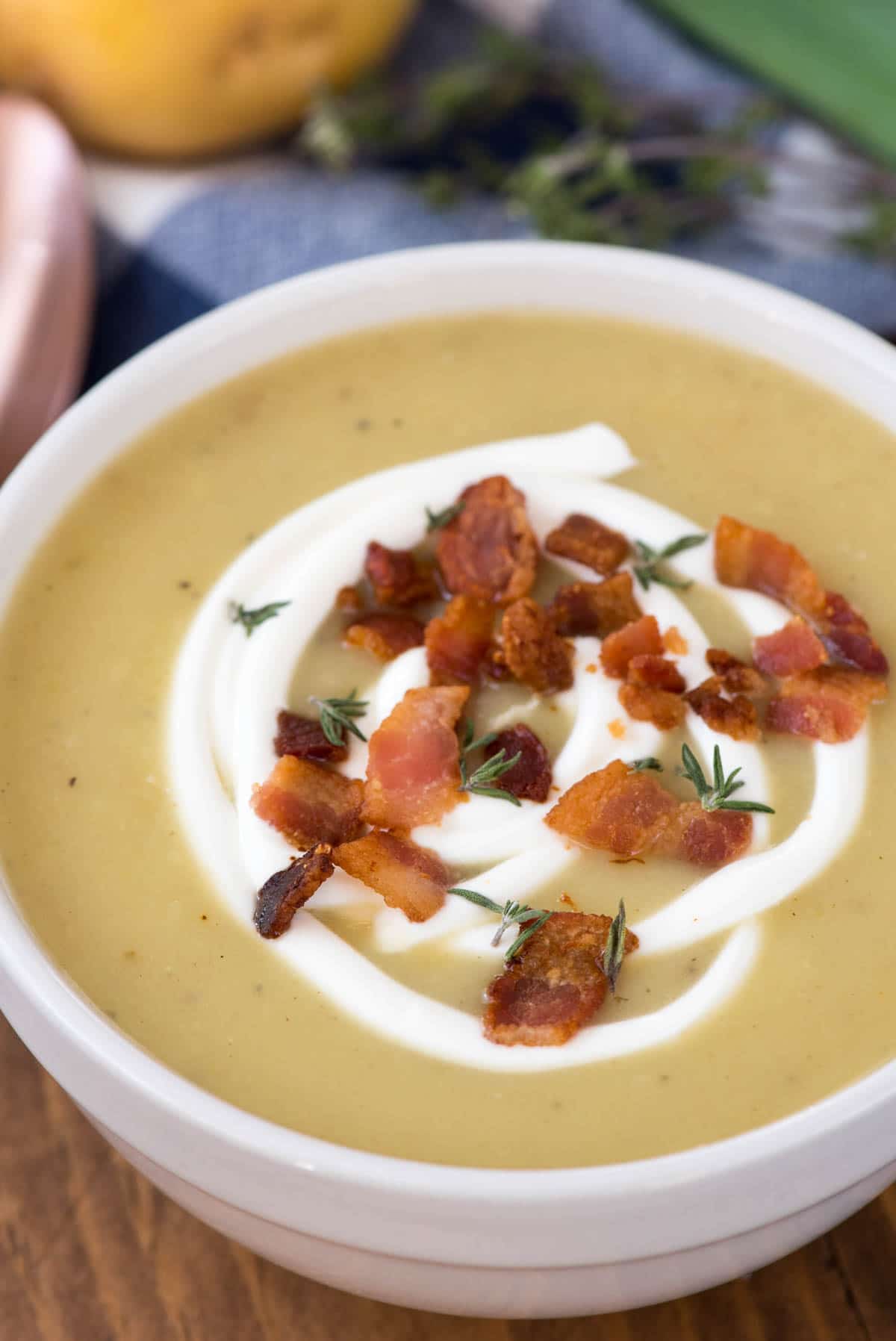 Potato and leek soup in a bowl topped with sour cream and bacon bits