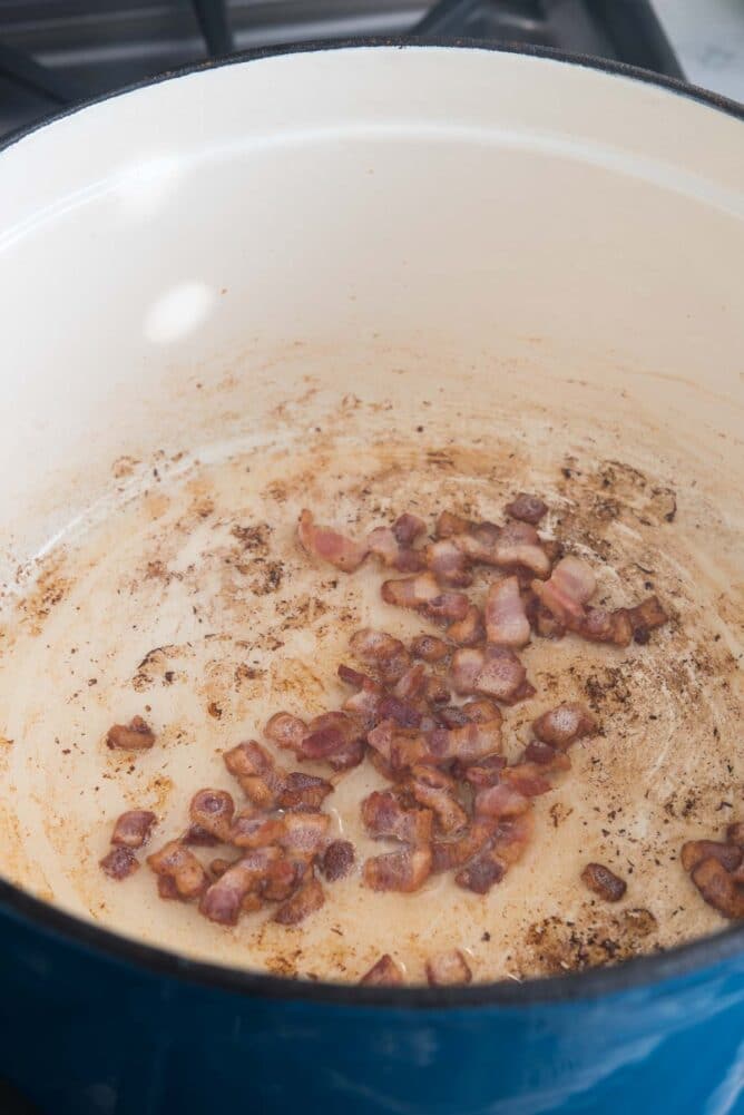 Bacon bits being cooked in a dutch oven