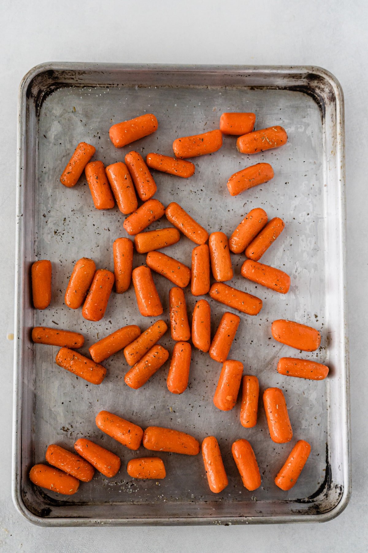carrots tossed with spices on cookie sheet.