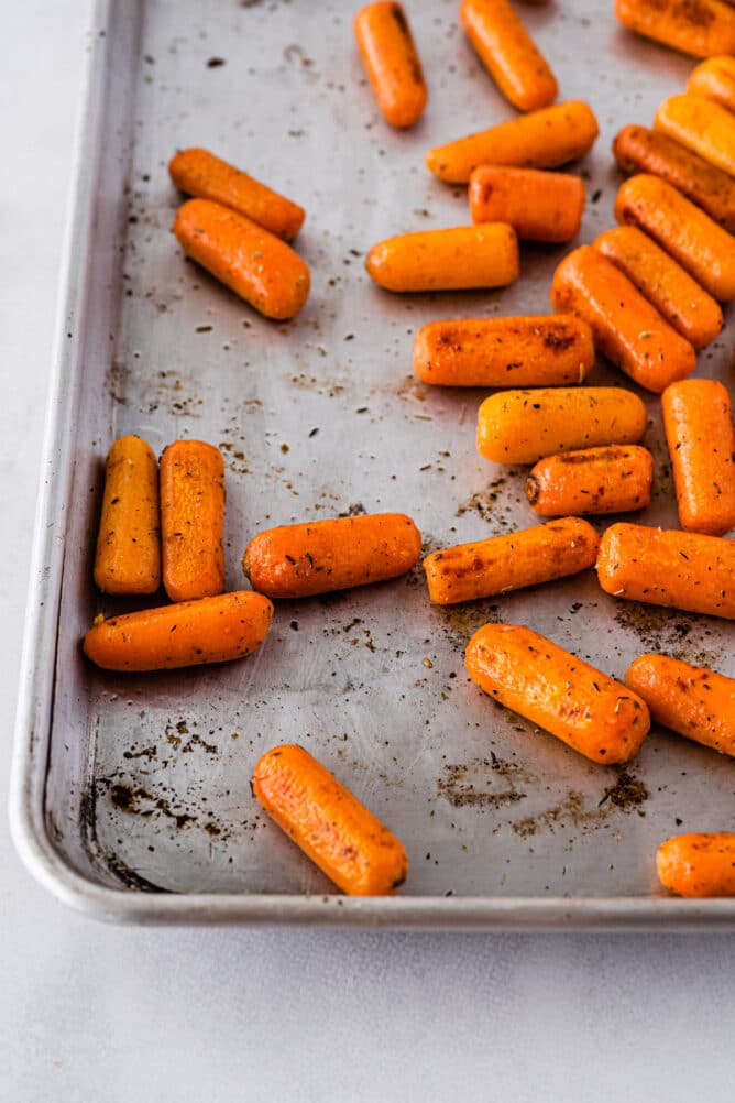 Sheet pan with roasted baby carrots spread out on it