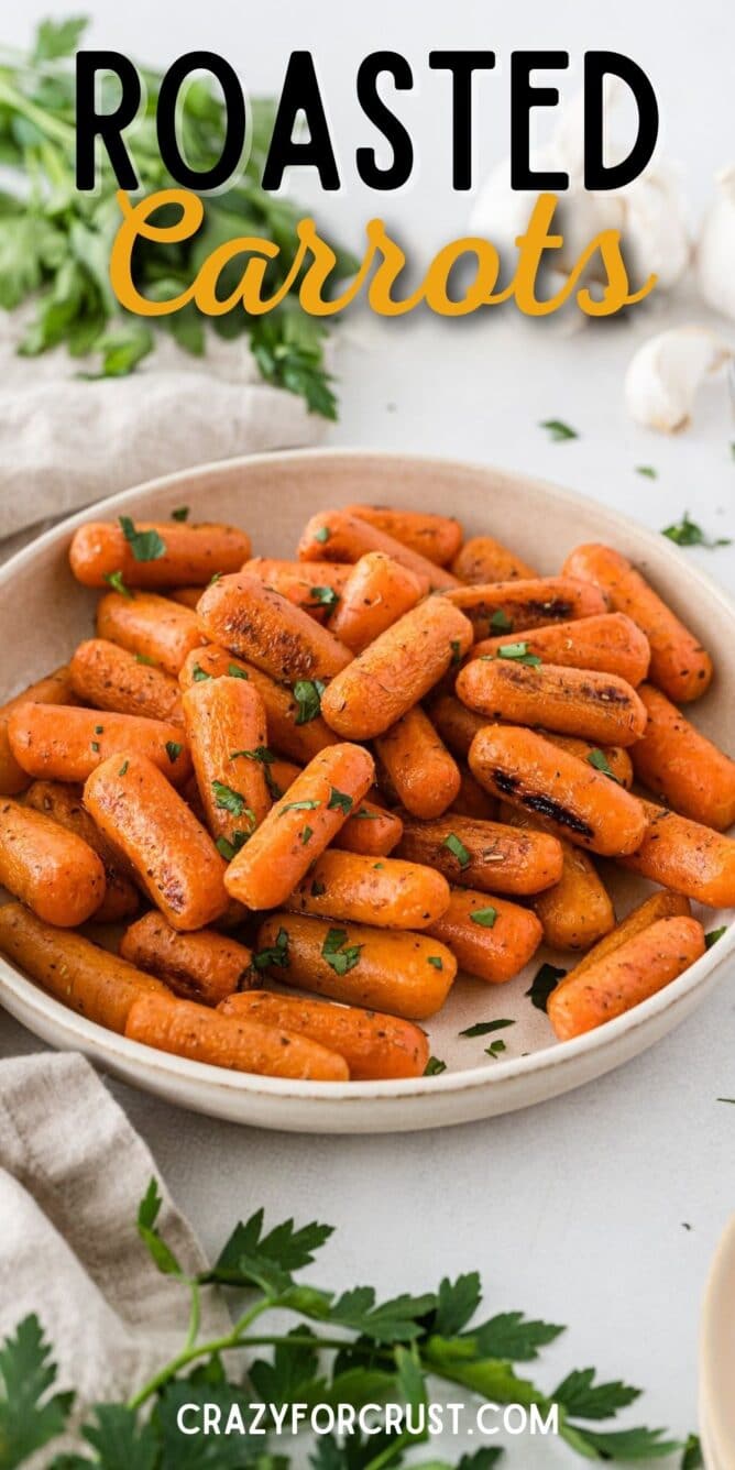 Roasted carrots in a white serving bowl with recipe title on top of image