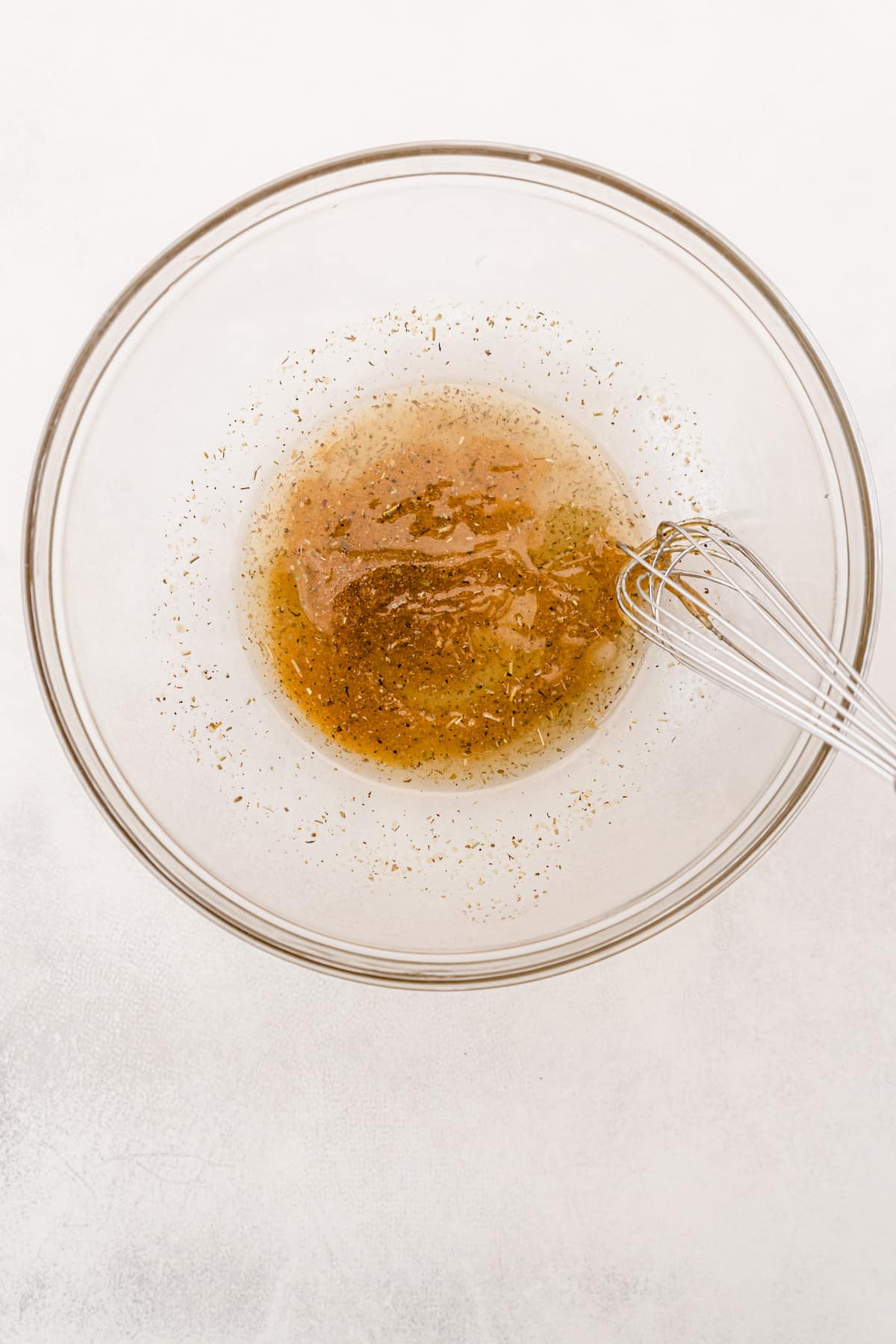 spices and oil in clear bowl with whisk.