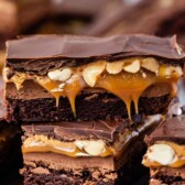 Stack of Snickers Brownies on a plate with recipe title on top of image