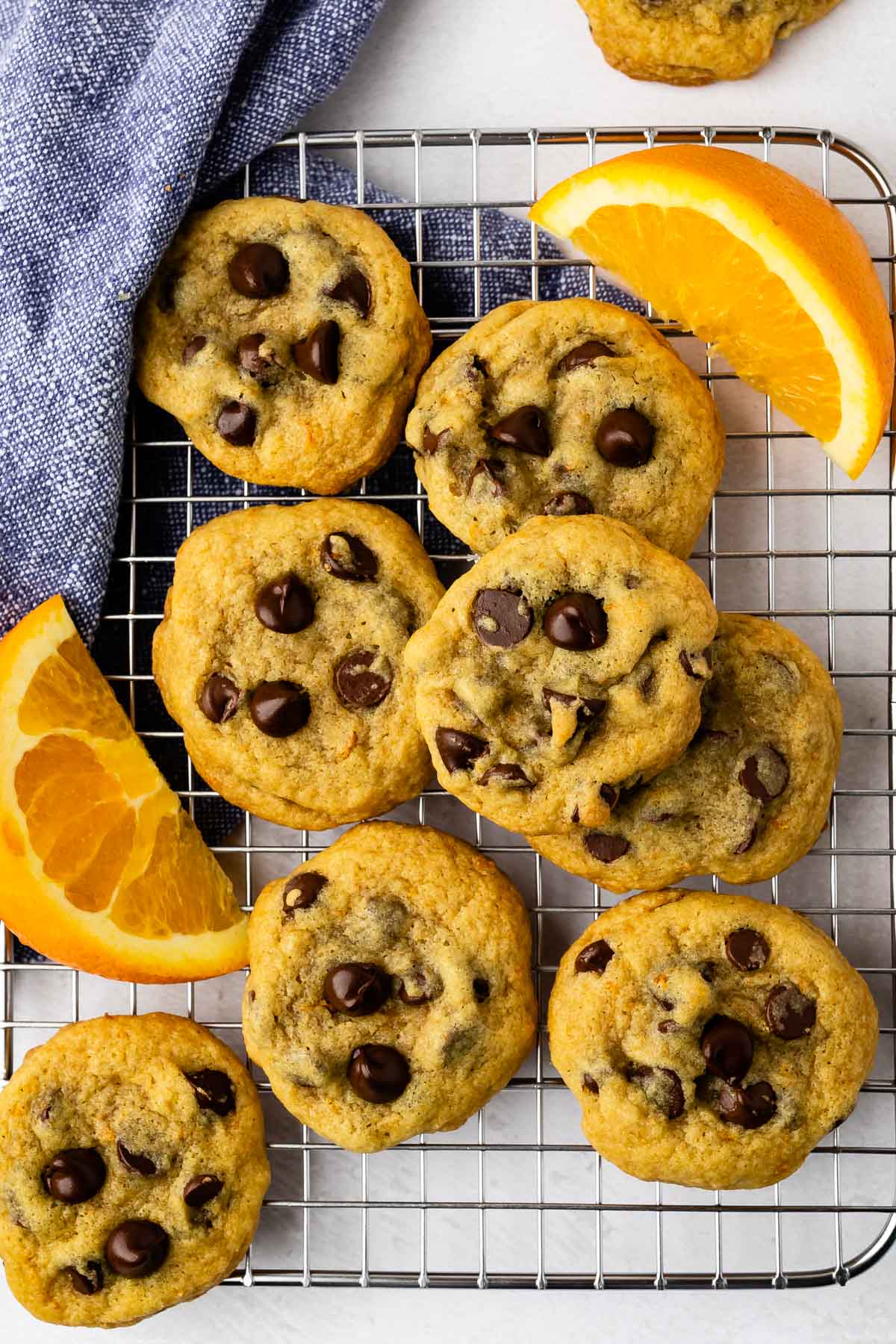 Overhead shot of chocolate chip orange cookies on cooling rack next to orange slices