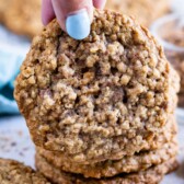 Hand holding oatmeal toffee cookie close to camera lens