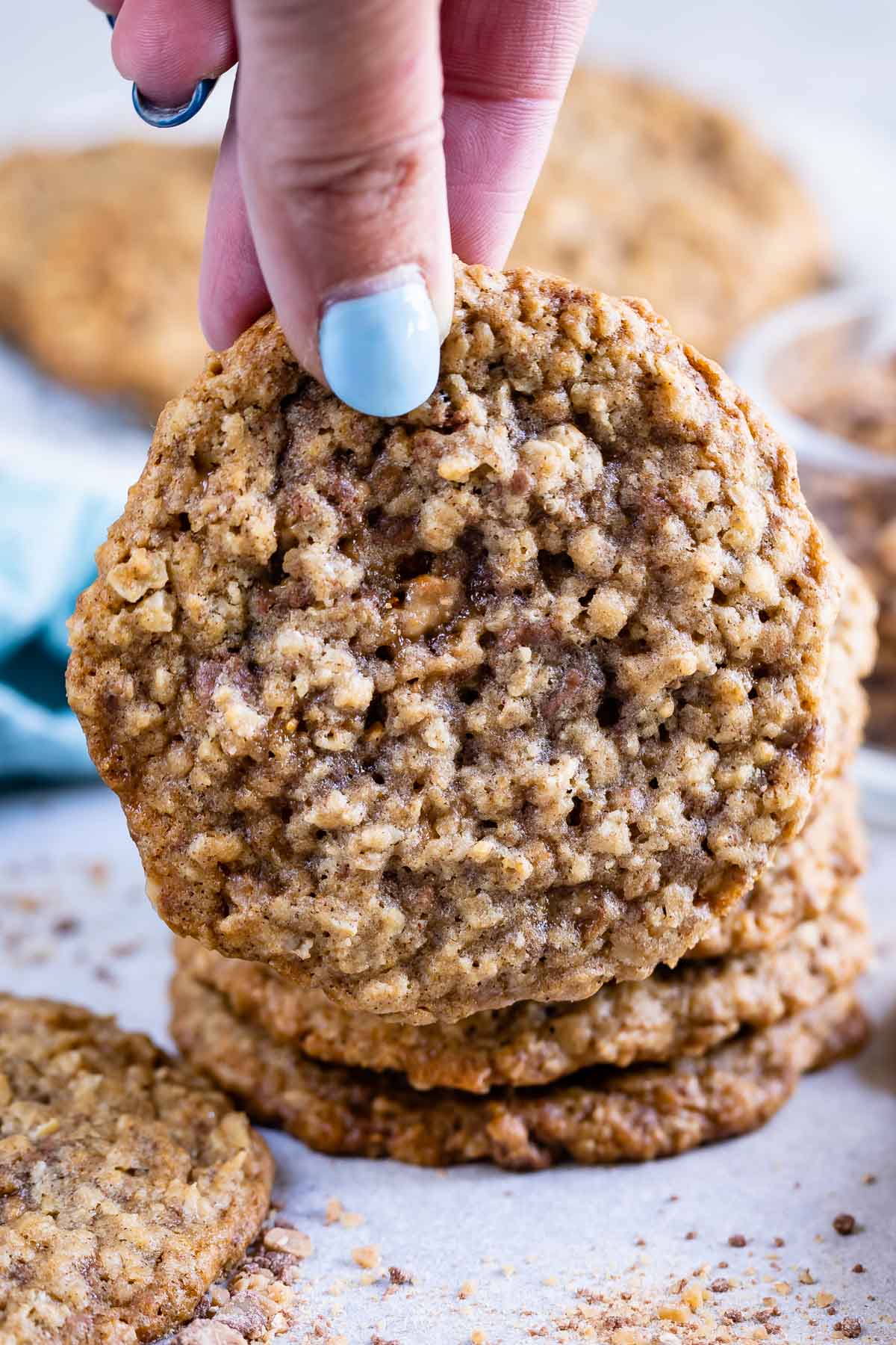 Hand holding oatmeal toffee cookie close to camera lens