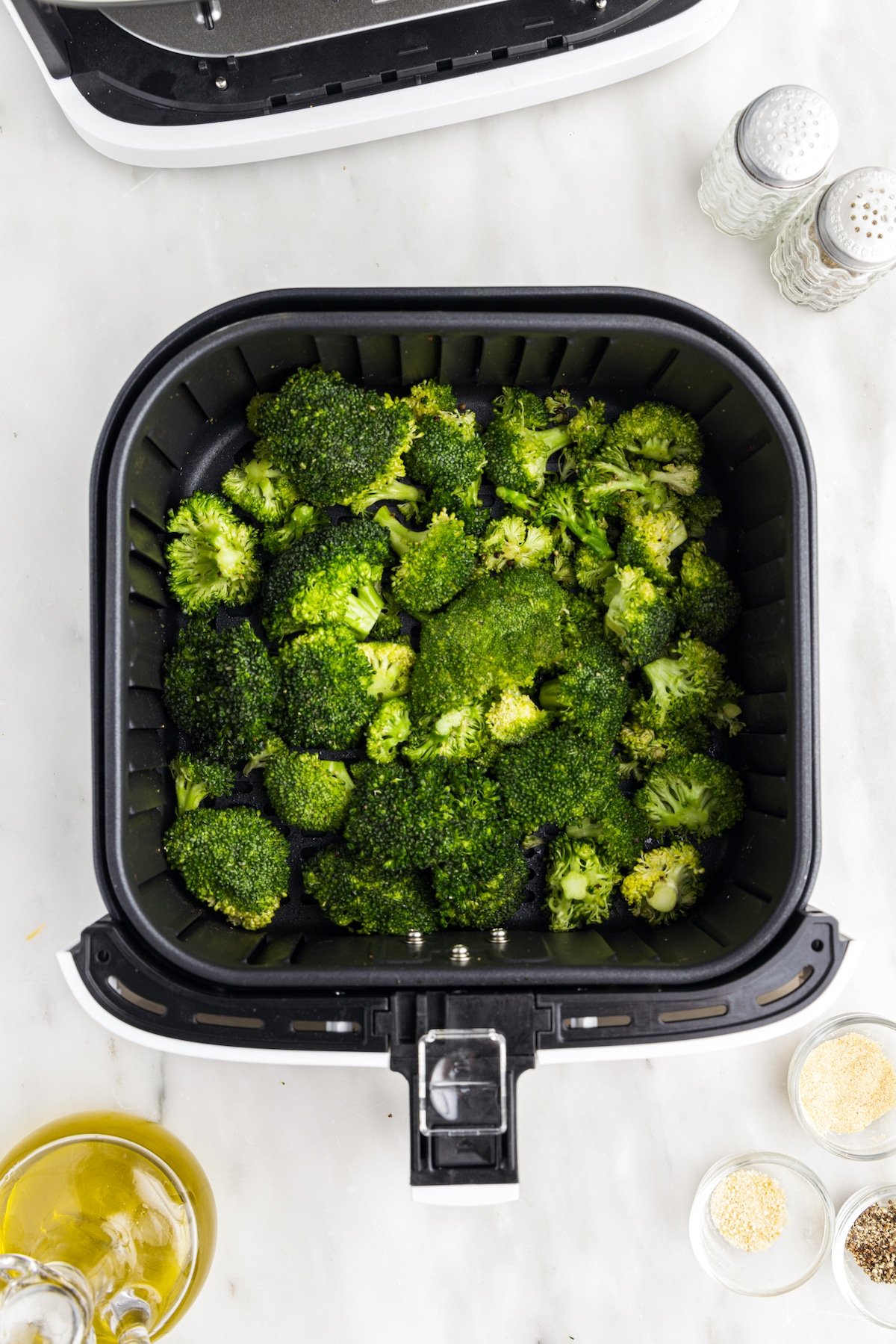 Overhead shot of broccoli inside the air fryer tray before cooking