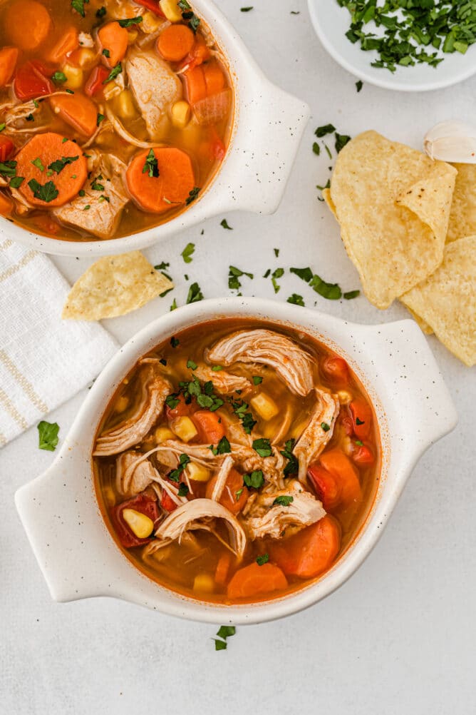 Overhead shot of bbq chicken soup in small dishes next to cilantro and tortilla chips