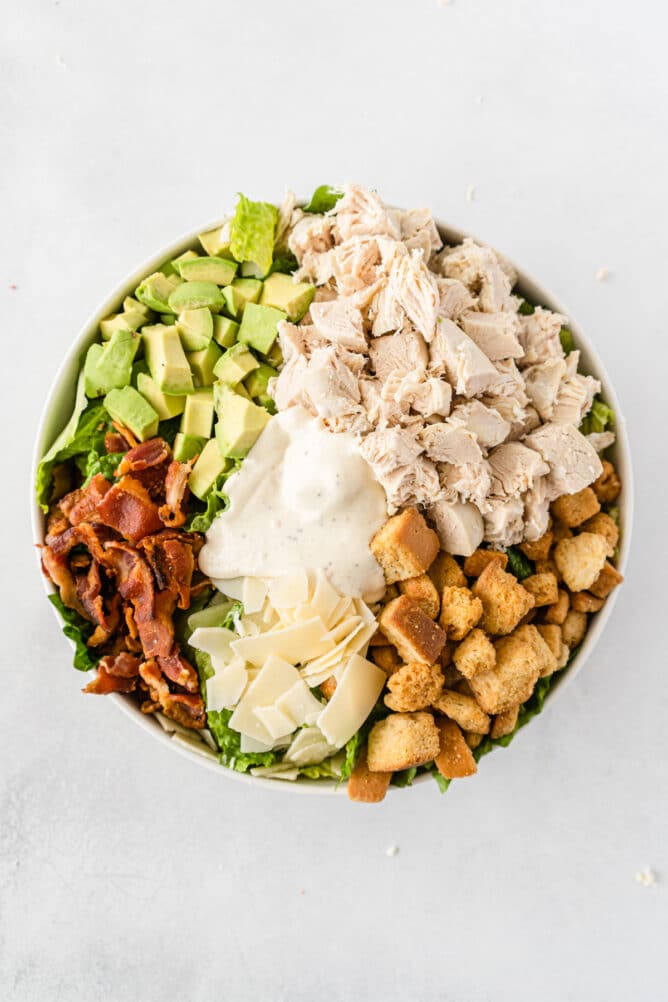 Overhead shot of caesar salad in a bowl before being mixed