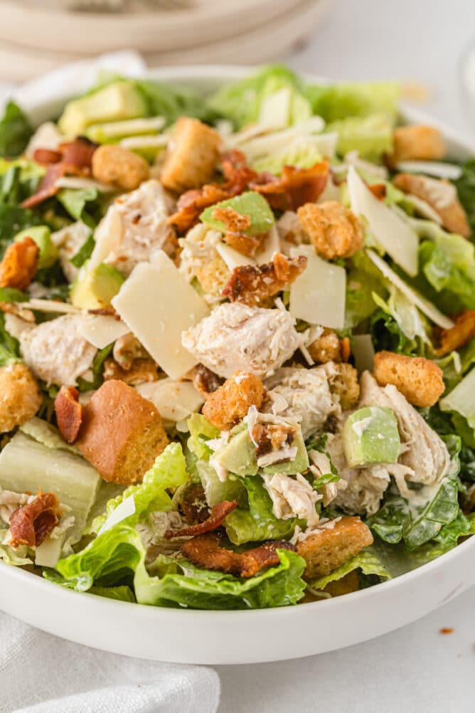 Close up shot of caesar salad with chicken and bacon in a bowl