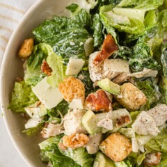 Close up shot of caesar salad with chicken and bacon in a bowl