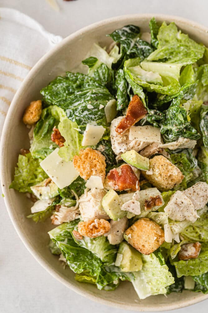 Close up shot of caesar salad with chicken and bacon in a bowl
