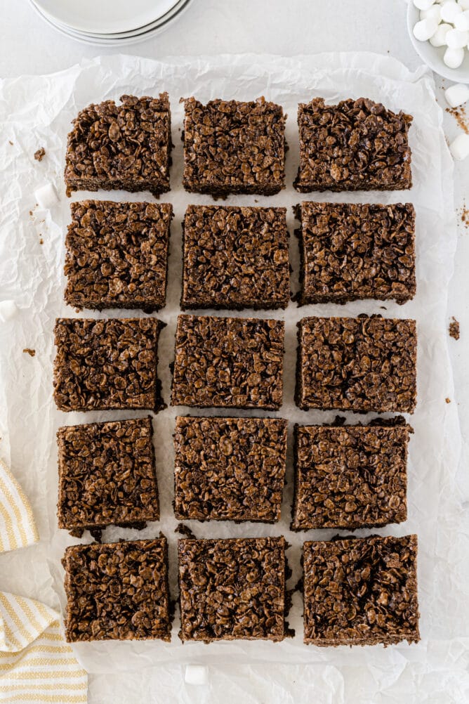 Overhead shot of chocolate rice krispie treats cut into squares on parchment paper