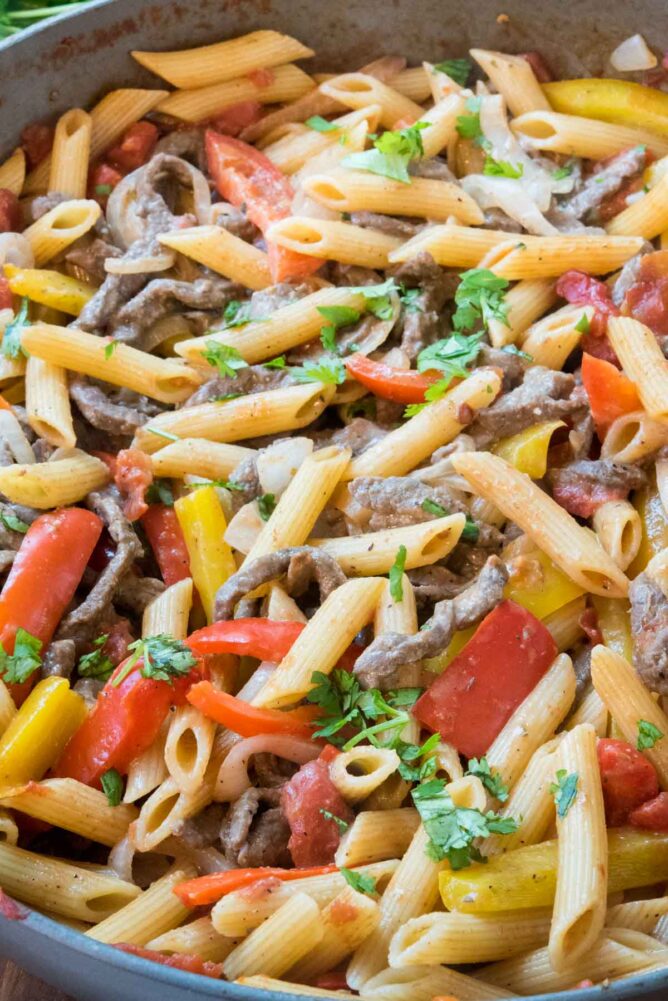 Close up shot of steak fajita pasta in a deep dish skillet