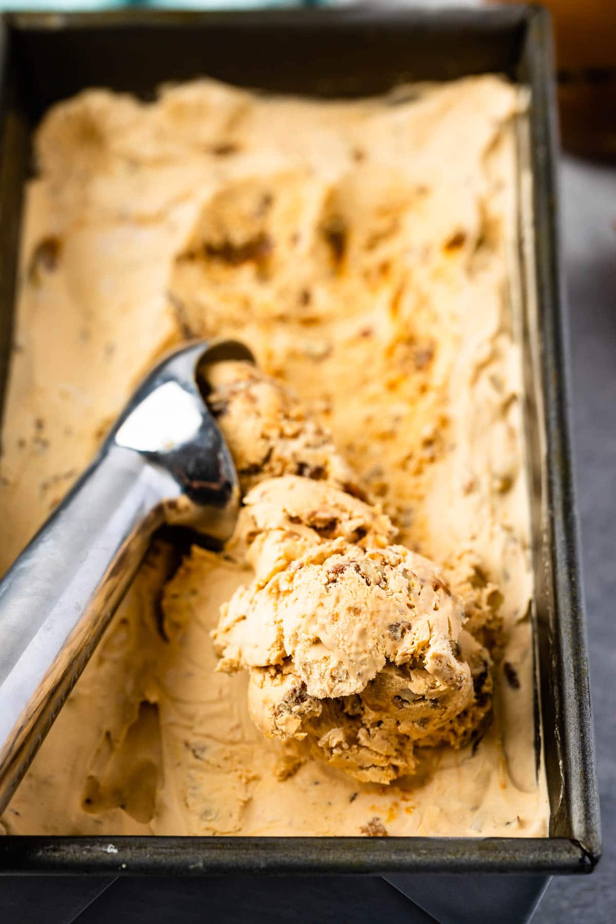 Dulce de leche ice cream being scooped out of container