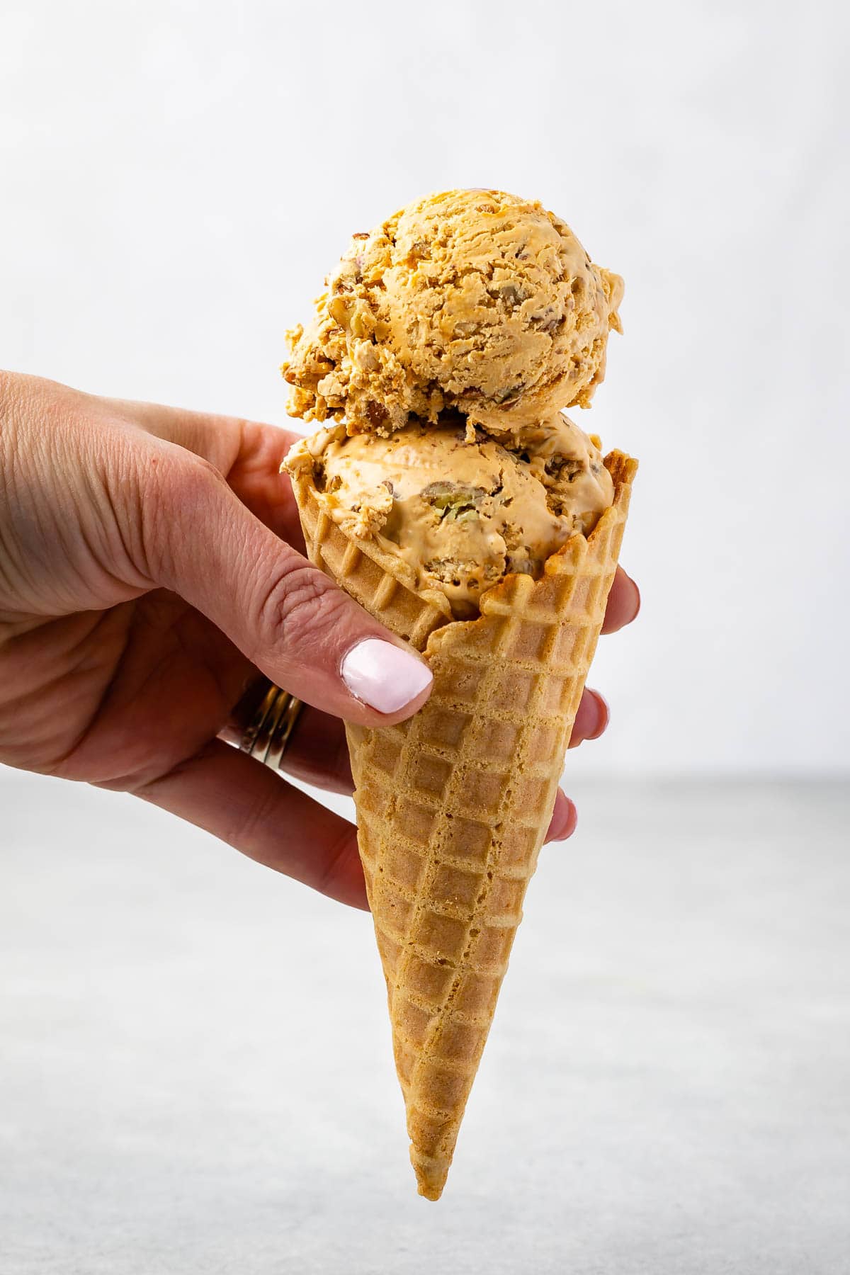 Hand holding a waffle cone filled with scoops of dulce de leche ice cream