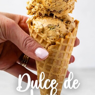 Hand holding a waffle cone filled with scoops of dulce de leche ice cream with recipe title on bottom of photo