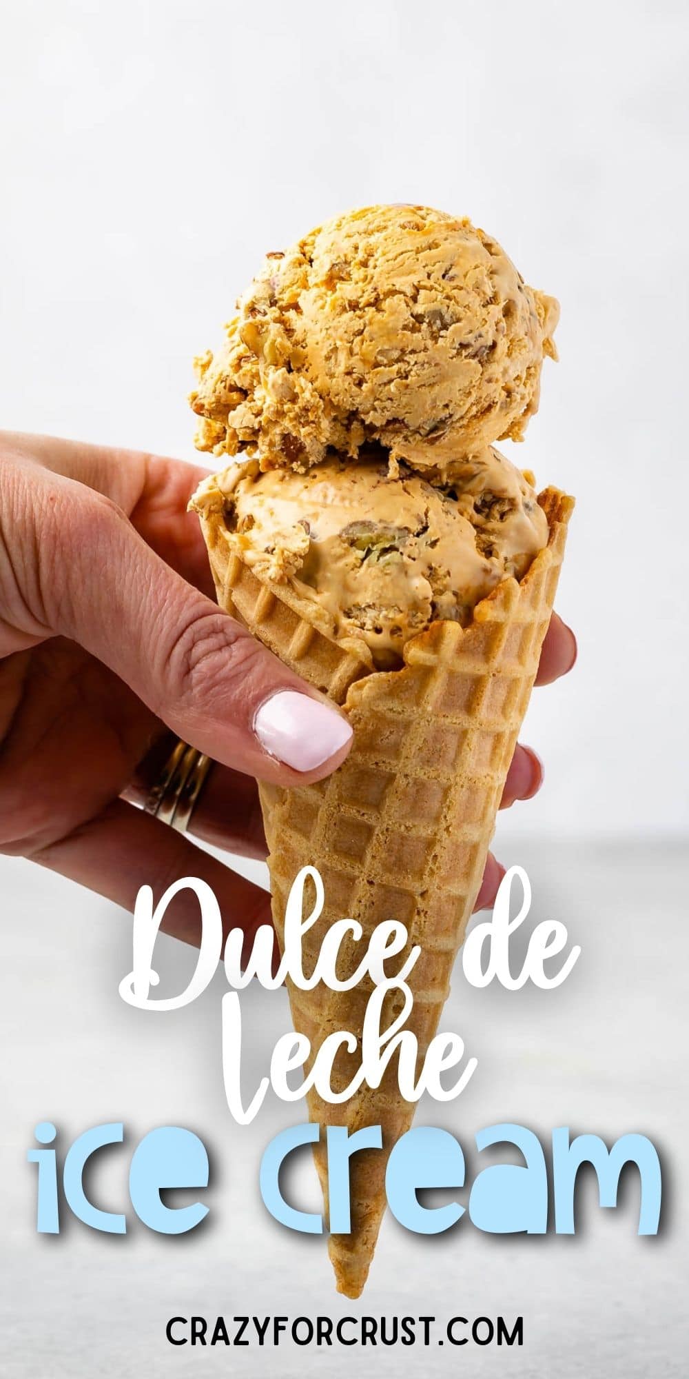 Hand holding a waffle cone filled with scoops of dulce de leche ice cream with recipe title on bottom of photo