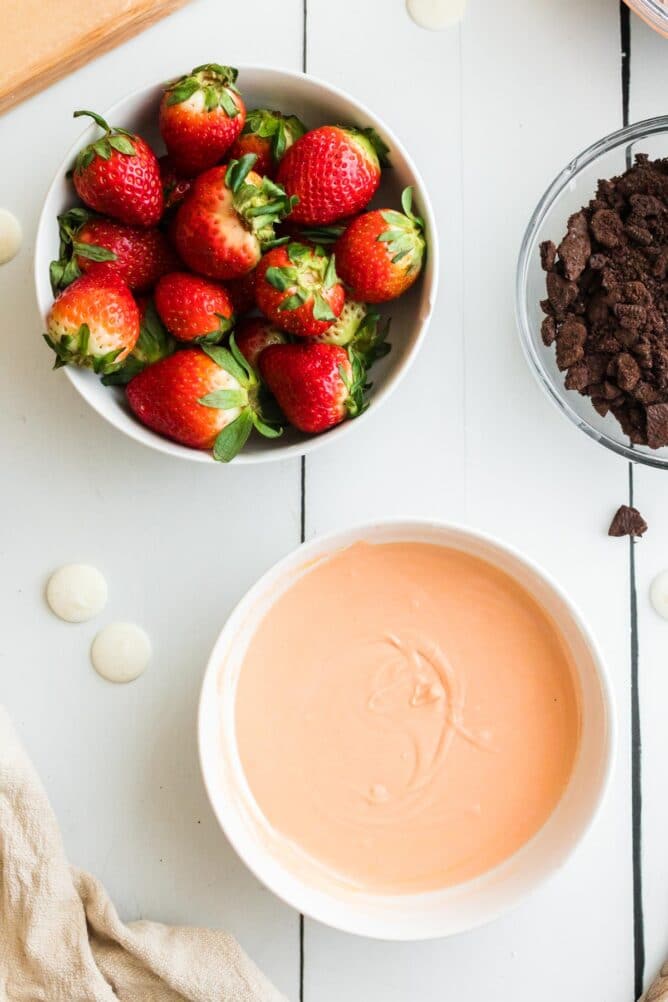 Overhead shot of bowl of strawberries and melted orange white chocolate