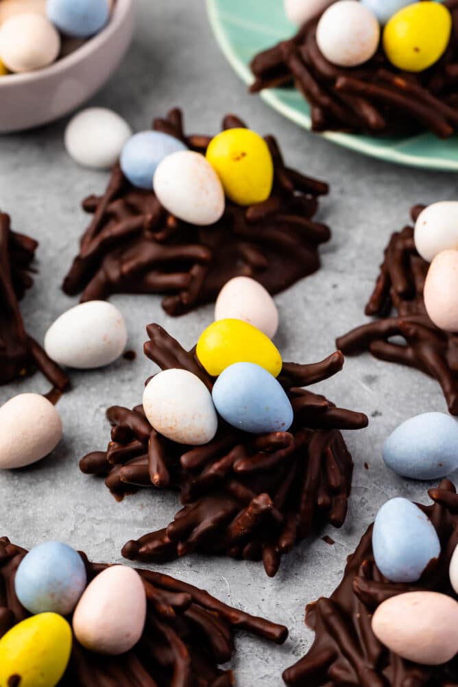 Lots of easter nest cookies on parchment paper topped with candy eggs
