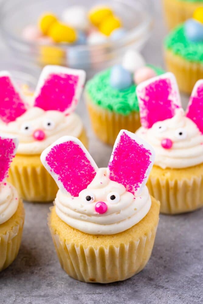 Four bunny cupcakes with easter nest cupcakes in the background