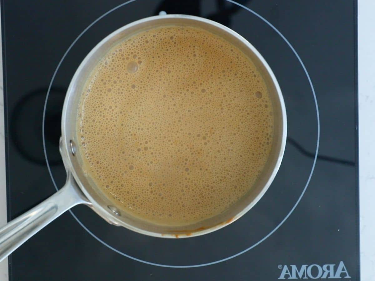 pan with dulce de leche and milk on hot plate