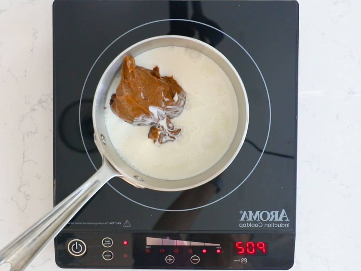 pan with dulce de leche and milk on hot plate