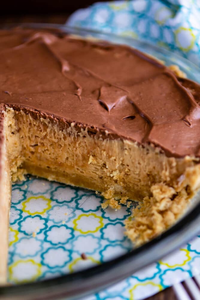 No bake peanut butter twix pie in glass pie dish with one slice missing
